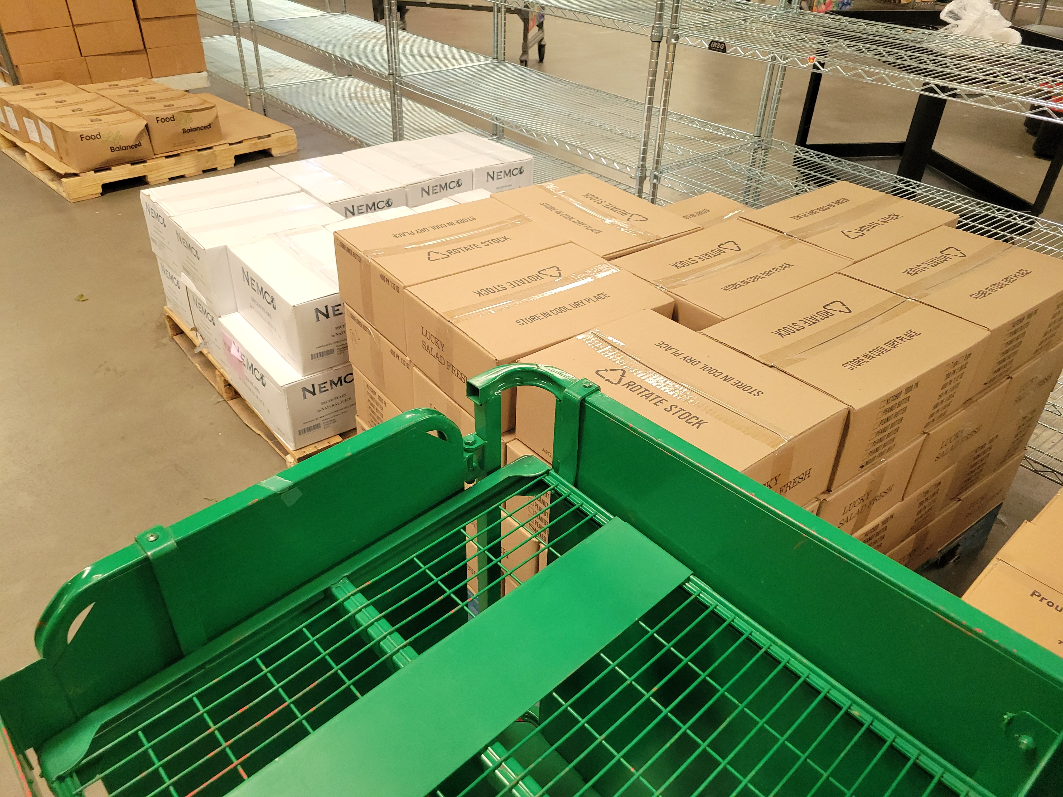 Pallets of food and water with signs that lists how many to put in a bag for the unhoused.